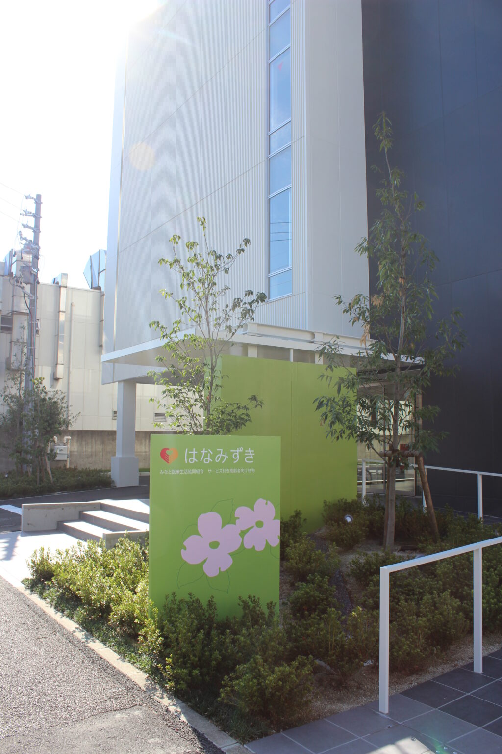 介護施設の建物外観。モダンな白い建物と緑のサイン看板が見える。
